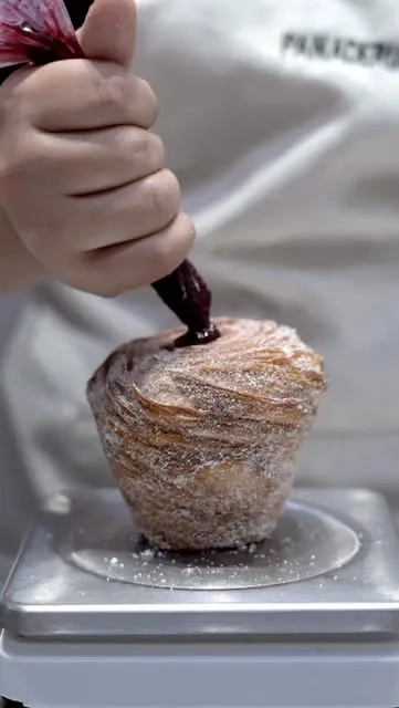 Cruffin siendo relleno con jalea de frutos rojos